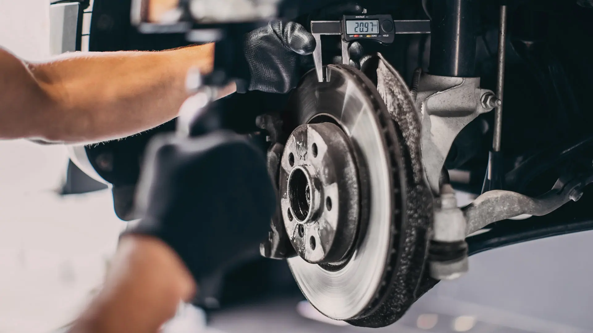 Technician measuring brake disc thickness on a MINI during a service inspection.