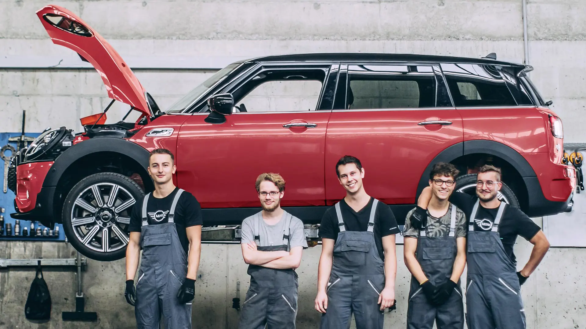 MINI service employees in front of a MINI Countryman on a lift.